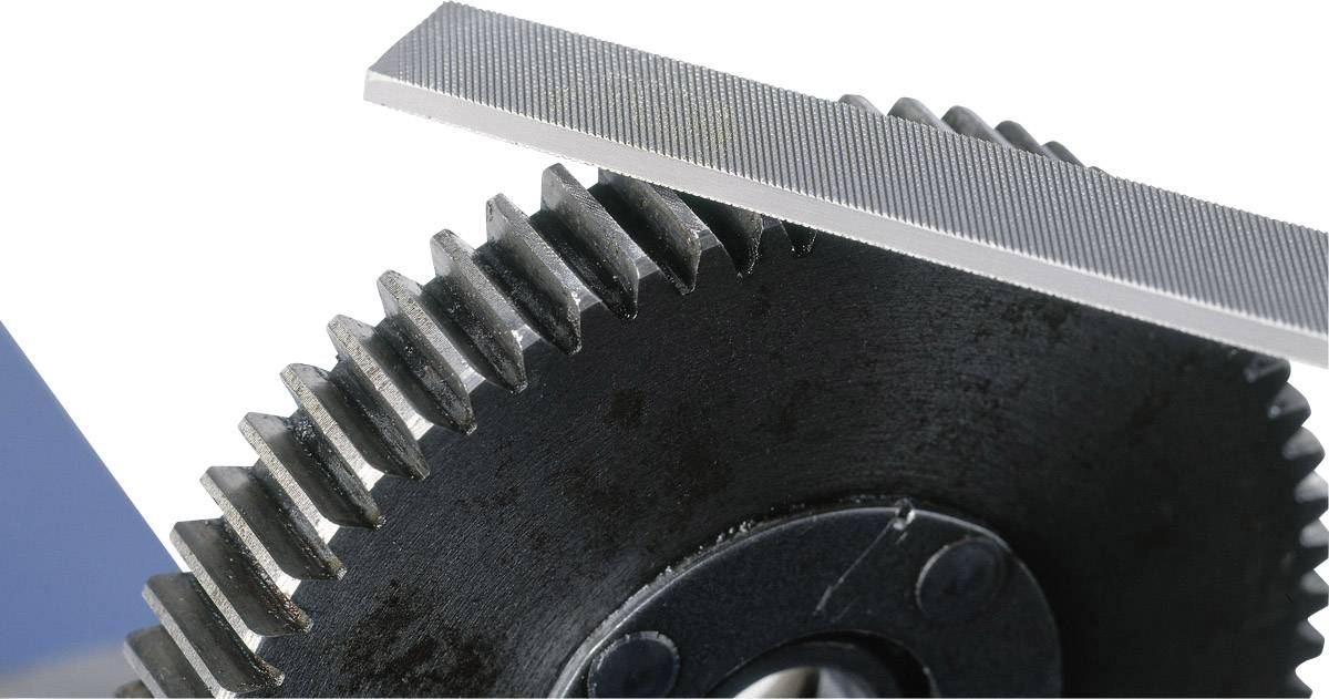 A coarse gear wheel being touched by a file, possibly to smooth or work its edges or teeth.