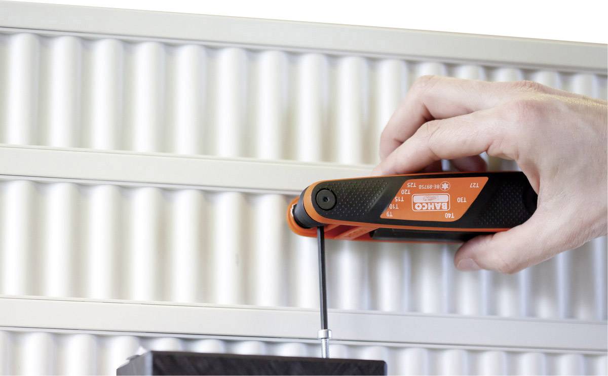 A human hand uses a measuring instrument on a metal grid.