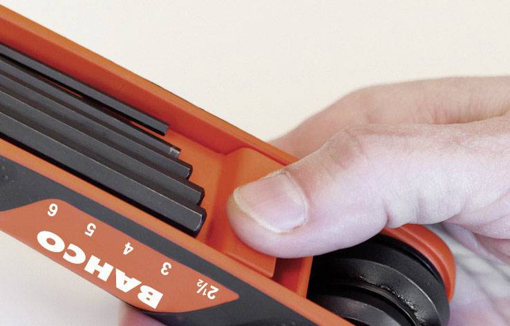 A hand is holding a multi-functional spanner with several hexagonal keys of different sizes from the 'Bahco' brand.