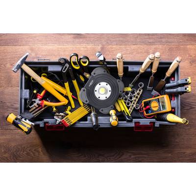 Toolbox with various hand tools such as a hammer, screwdriver, tape measure and pliers on a wooden floor.