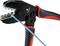 A crimping pliers with rubber grips in red and black. A blue cable is placed between the jaws, ready to be crimped.