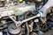 A person is tightening the bolts on a vehicle engine with a torque wrench. Part of the engine is visible.