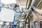 A technician is adjusting a machine in a factory hall using a torque wrench. Pipes and measuring instruments are visible in the background.