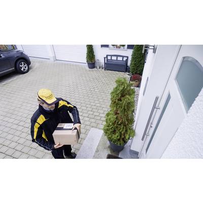 A delivery person in a yellow uniform is carrying a package to the front door of a house. In the background, a car and a closed garage can be seen.