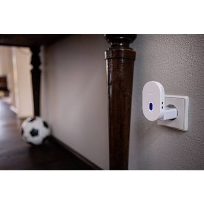 A Wi-Fi repeater is plugged into the wall socket. A blurry football lies on the floor in the background.