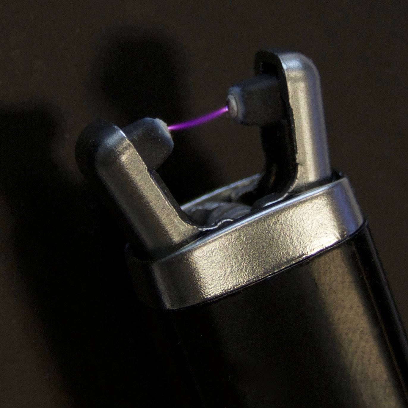 An electric lighter with an open lid generates a violet electric arc which is used for ignition.