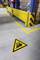 'Warning sign on the floor of a warehouse: Caution Forklift. Yellow barrier and cardboard boxes in the background.'