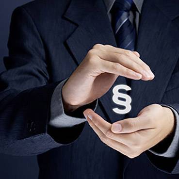 A man in a suit carefully holds a floating paragraph symbol between his hands, symbolising legal matters.