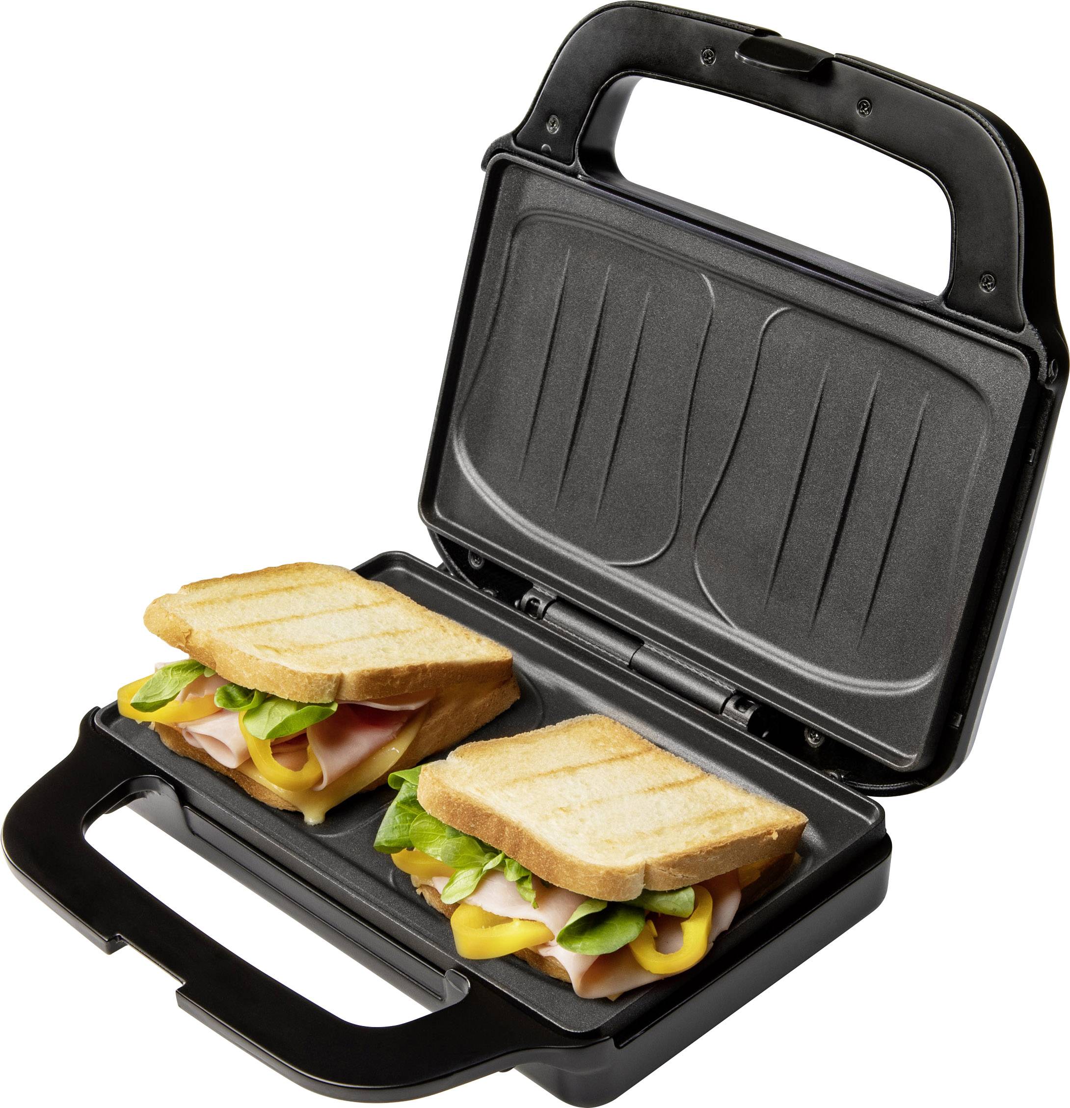 A sandwich toaster with two filled sandwiches containing ham, cheese, and lettuce. They are currently being heated and toasted.