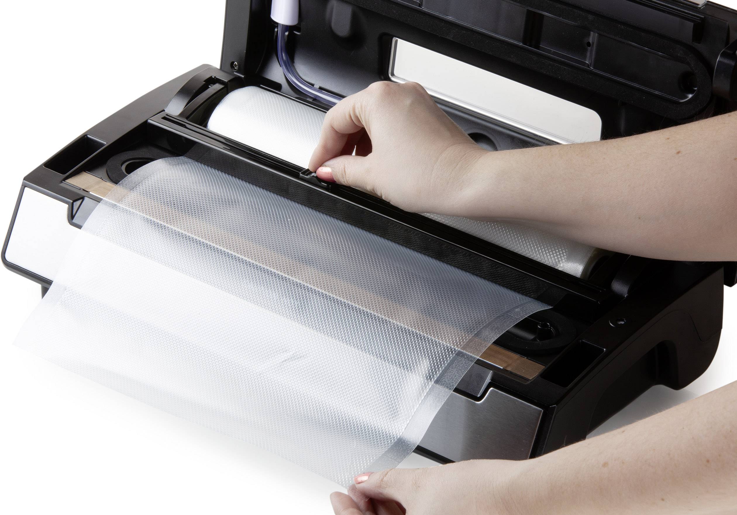 A person places a film in a vacuum sealer to hermetically seal food for storage.