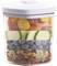 A glass container with a lid shows layers of colourful vegetables and fruit: carrots, courgettes, blueberries, nuts.