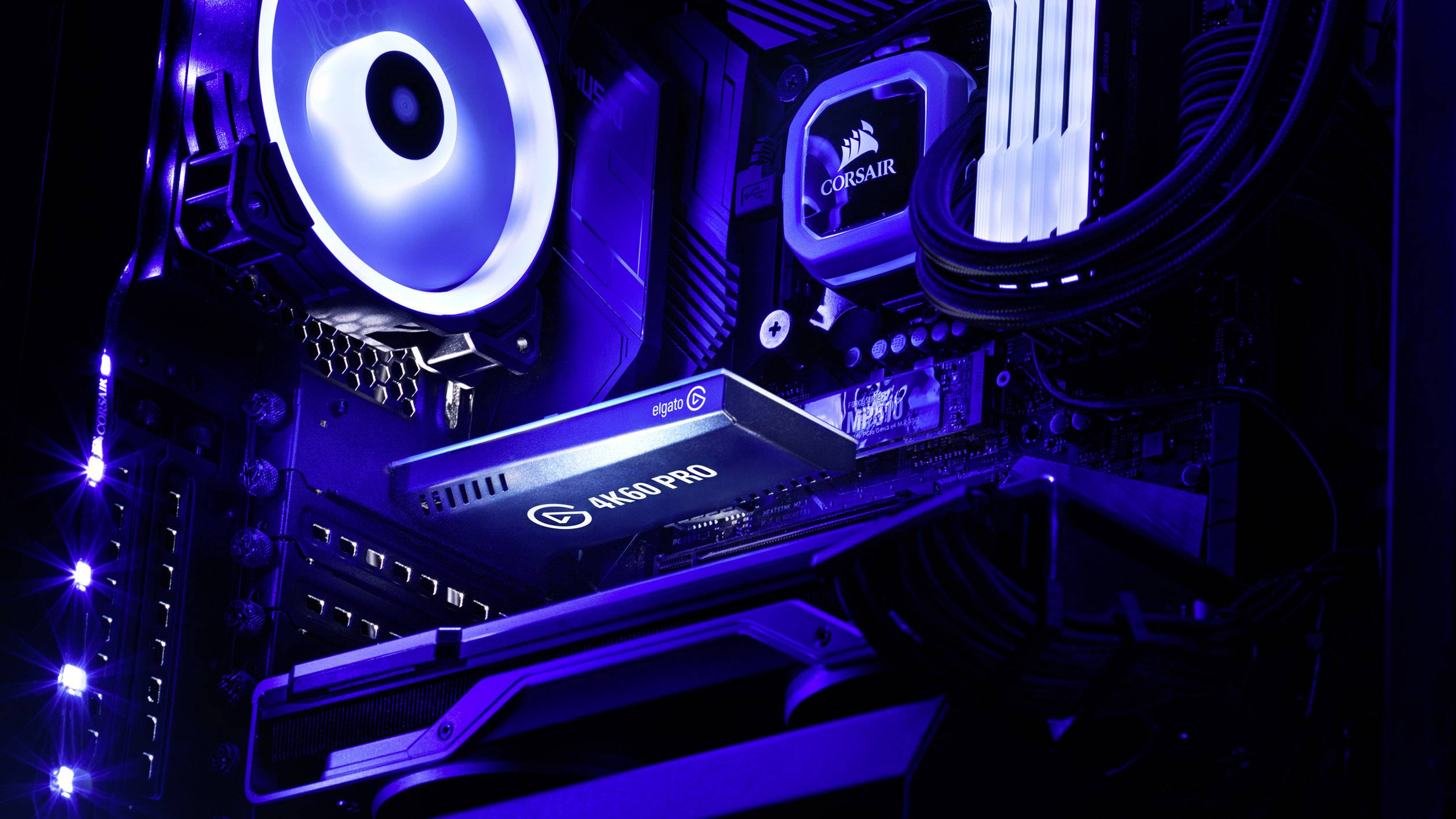 A gaming PC with illuminated components, including a graphics processor, a fan, and memory modules, bathed in blue light.