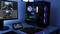 A gaming PC with RGB lighting sits on a table next to a monitor displaying a game. A controller rests beside it.