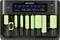 Battery charger with eight green batteries in various sizes, displaying charge status and voltage on a digital screen.