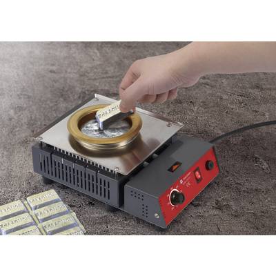 A hand is holding an aluminium part and dipping it into molten lead at a soldering station, likely in preparation for soldering.
