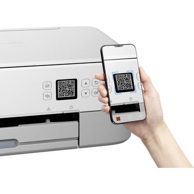 A smartphone scans a QR code on a printer. The screen displays the scanned QR code within a blue frame.