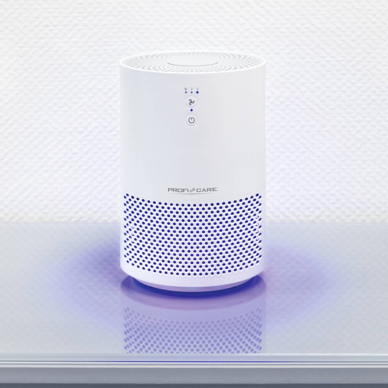 A white air purifier on a table, minimalist in design with blue ventilation slots at the bottom, switched on.