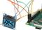 'Small OLED display connected to a green microcontroller board via several coloured cables, with the "JOY-IT" inscription.'