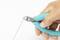 A hand is holding a wire cutter with a turquoise handle, cutting a wire.