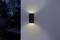 Exterior wall light mounted on a wall, casting a warm glow upwards and downwards, illuminating a dark, tranquil street.