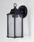 Black wall light made of metal and glass in a classic lantern style, mounted on a white wall.