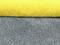 A yellow and a grey terry towel are lying on top of each other.