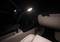 A car interior at night. A flexible reading lamp gently illuminates the front area of the vehicle.