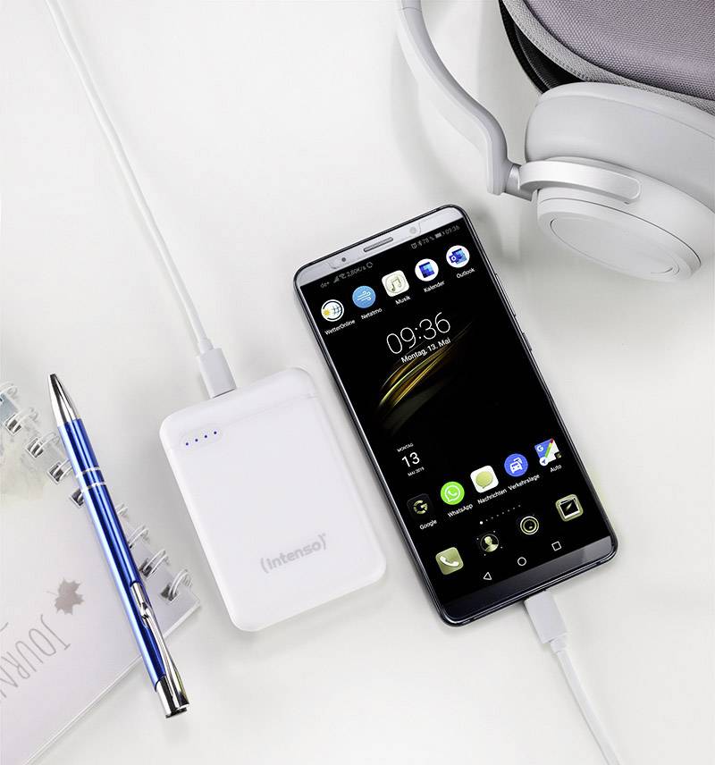 Smartphone and power bank on a white background, connected by a charging cable; alongside earphones, calendar, and ballpoint pen.