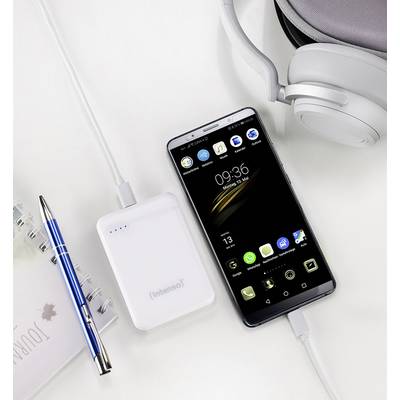 Smartphone and power bank on a white background, connected by a charging cable; alongside earphones, calendar, and ballpoint pen.