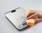 'Hand wipes coffee grounds off digital kitchen scales with a yellow cloth.'