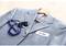 Grey suit with name badge 'Mr. Miller', bunch of keys and blue lanyard on a wooden coat hanger.