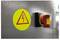 Warning sign on a grey surface with a lightning symbol and a red emergency stop button beside it, indicating electrical hazard and quick shutdown.