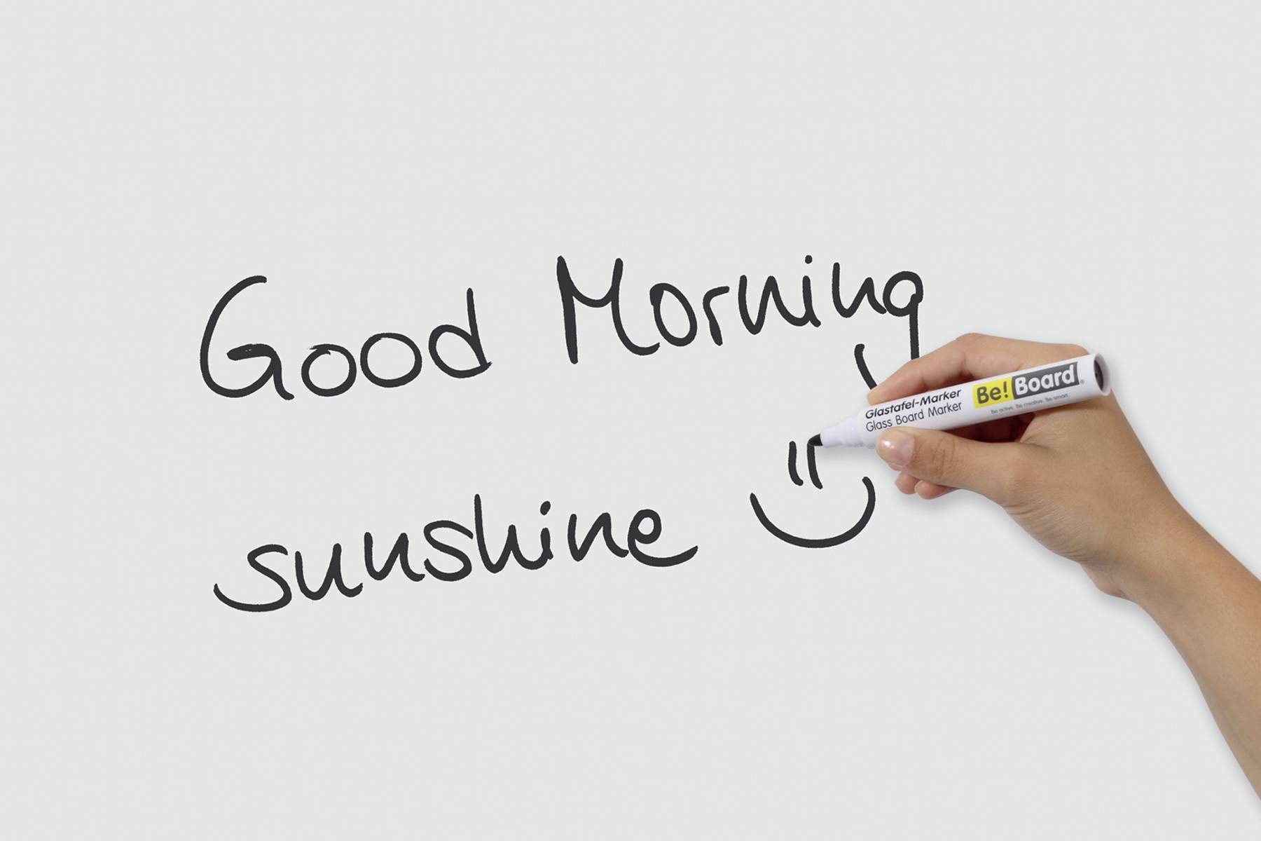 Hand writes on whiteboard 'Good Morning sunshine :)'