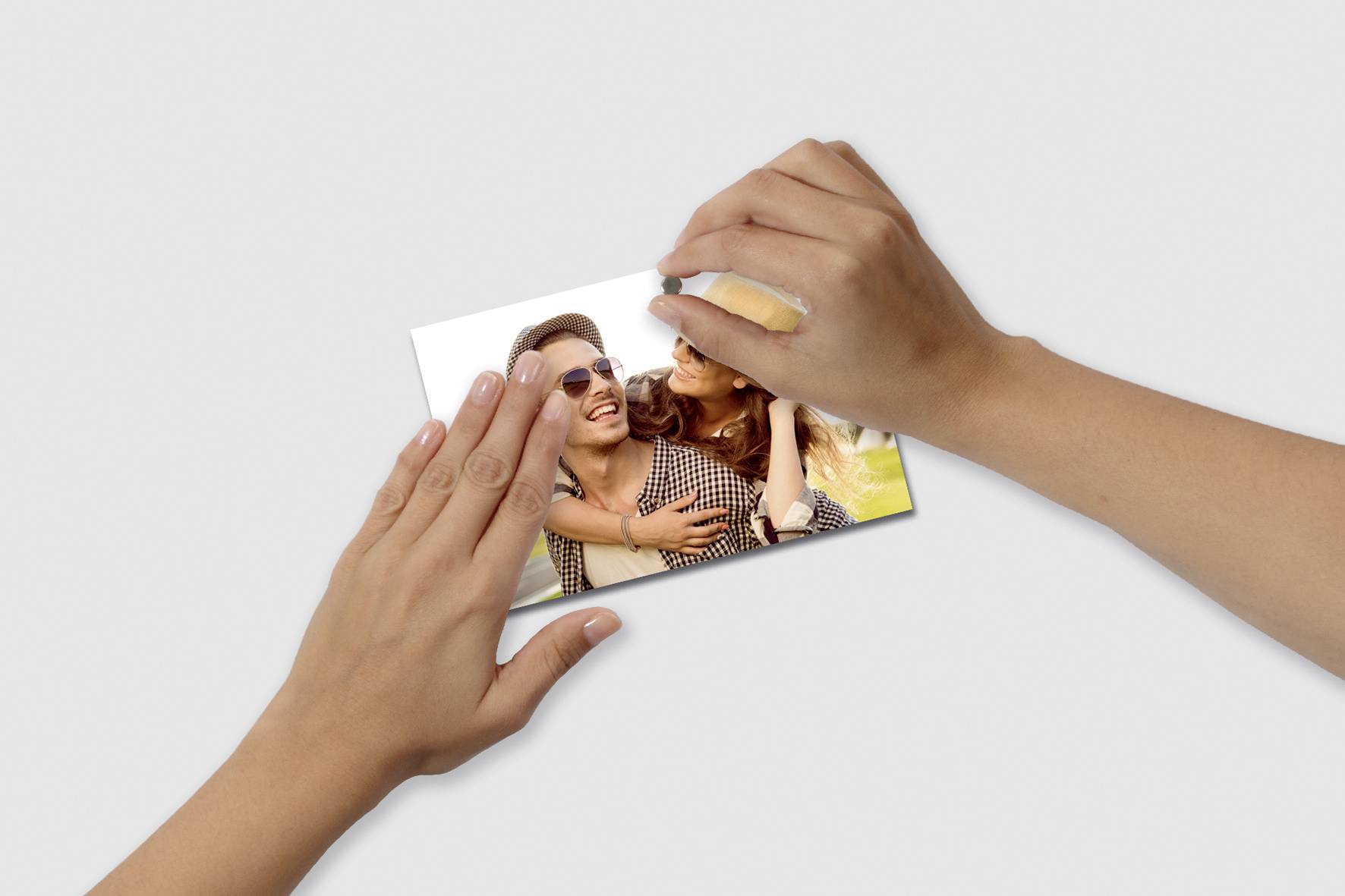 Hands holding a photograph of two smiling people embracing.