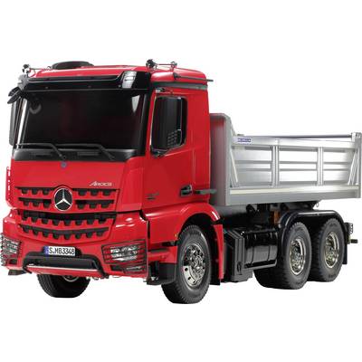 Red lorry with a Mercedes logo, six wheels and a silver cargo area. Front view, suggesting a road journey.