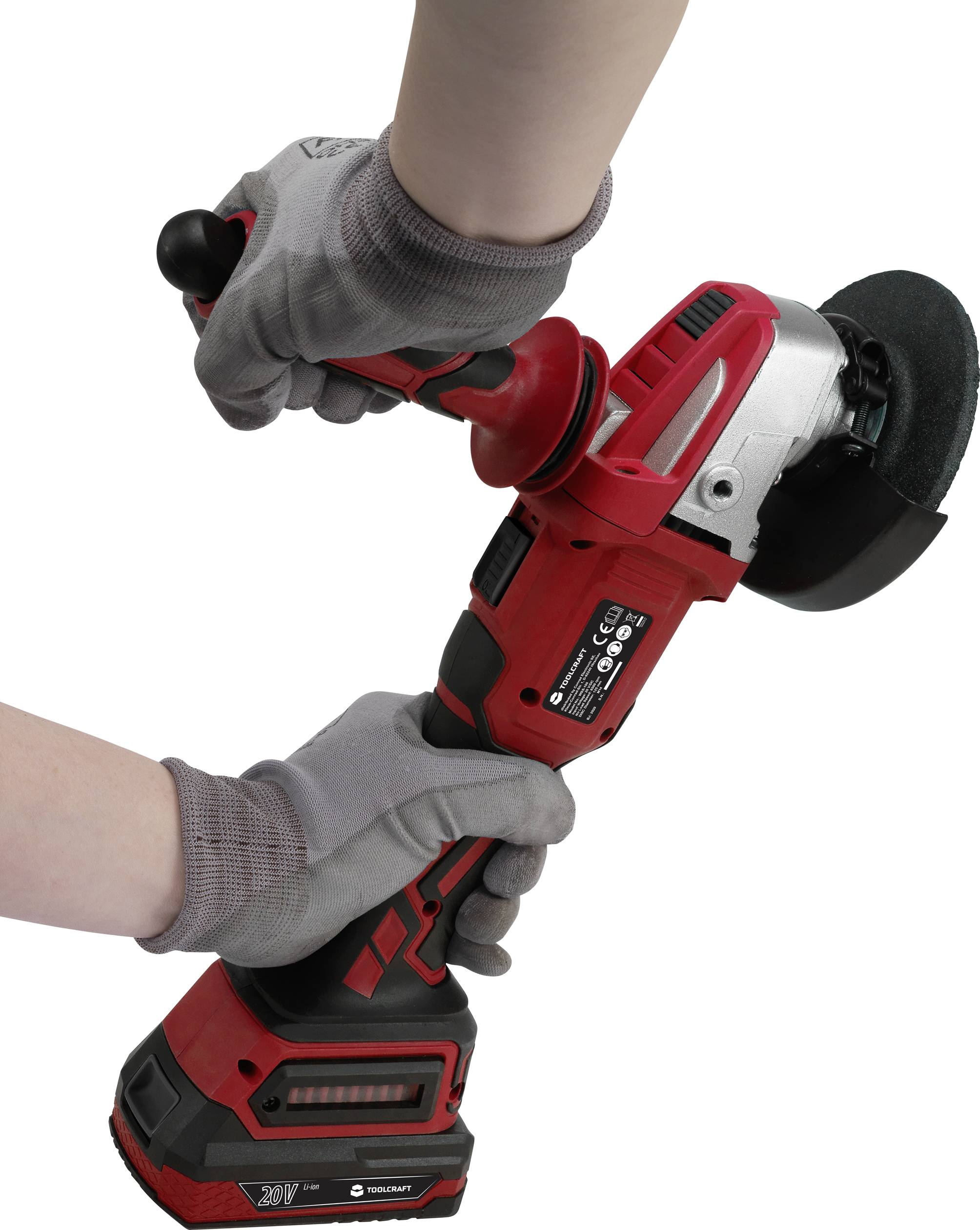 A person is holding a red angle grinder with both hands. The grinder is switched on and is being operated with protective gloves.