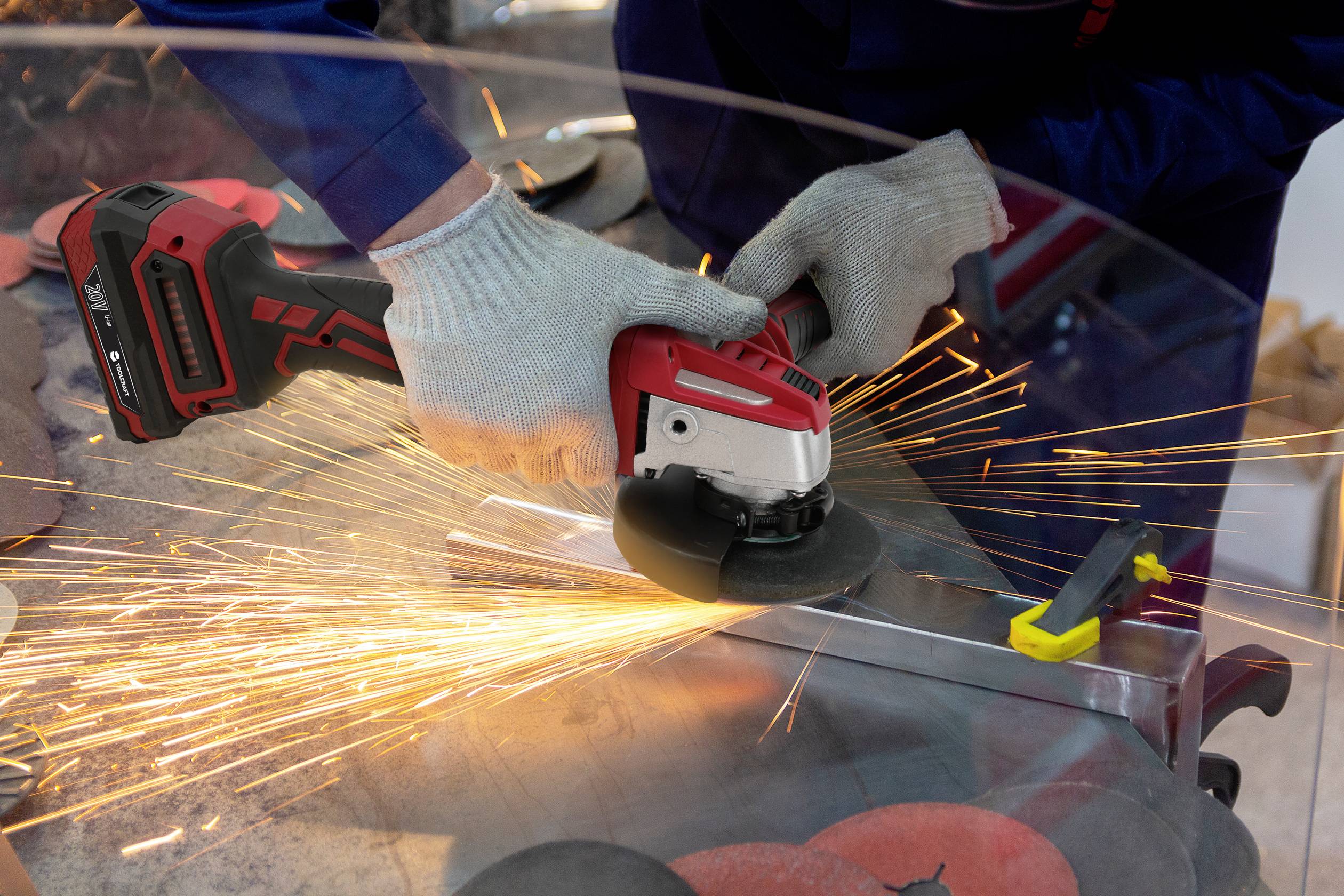 A person is grinding a metal bar with an electric angle grinder while sparks are flying. They are wearing grey gloves.