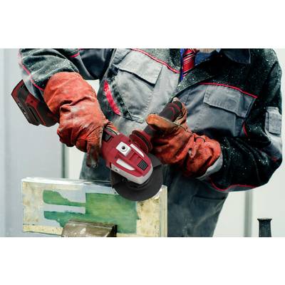 A worker in protective clothing is grinding metal with an angle grinder in a workshop.