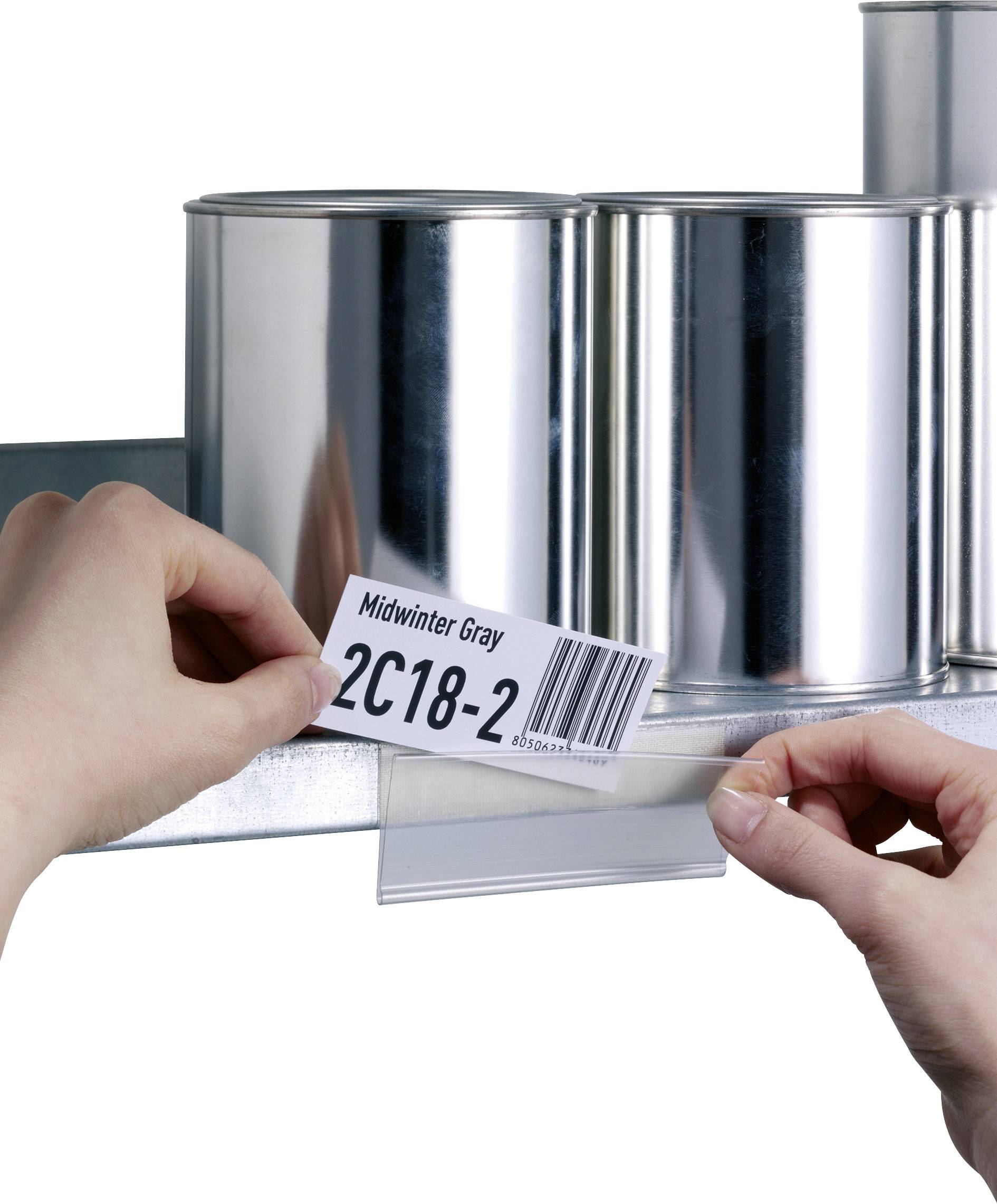 Two hands are attaching a label reading 'Midwinter Gray 2C18-2' to a shelf with silver tins placed on it.