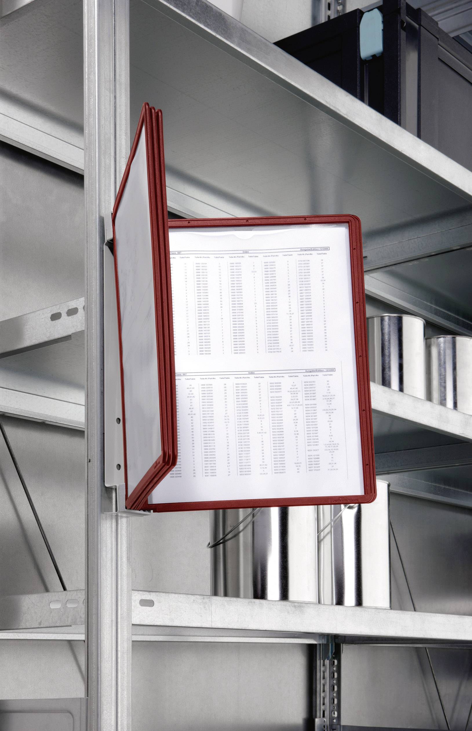A red clear file holder is attached to a metal shelving unit and displays several printed pages with tables.