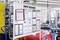 An information board in a factory, containing various documents and diagrams, including safety regulations and process overviews.