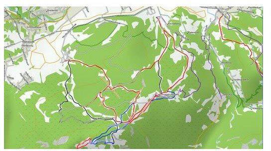 Map of a green landscape with hiking trails marked in various colours. Main paths traverse white areas through dense forests.