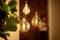 'Three hanging light bulbs glow warmly in a room, with a person blurred in the background.'
