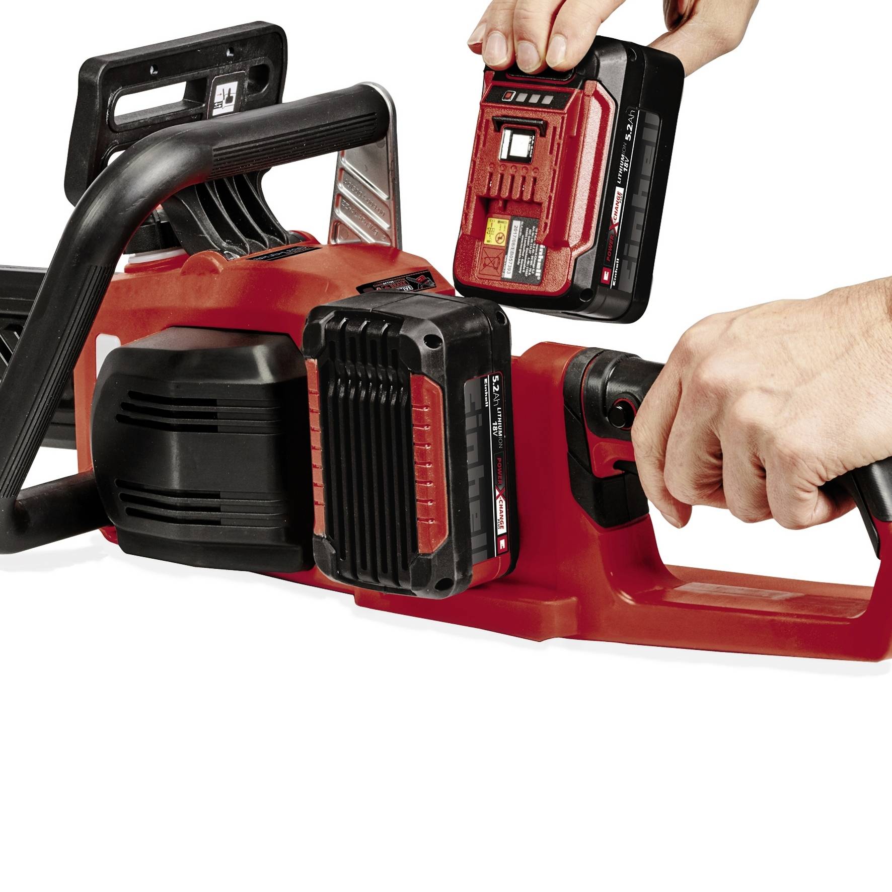 A person is inserting a battery into a red cordless chainsaw. The chainsaw is ready for outdoor use.