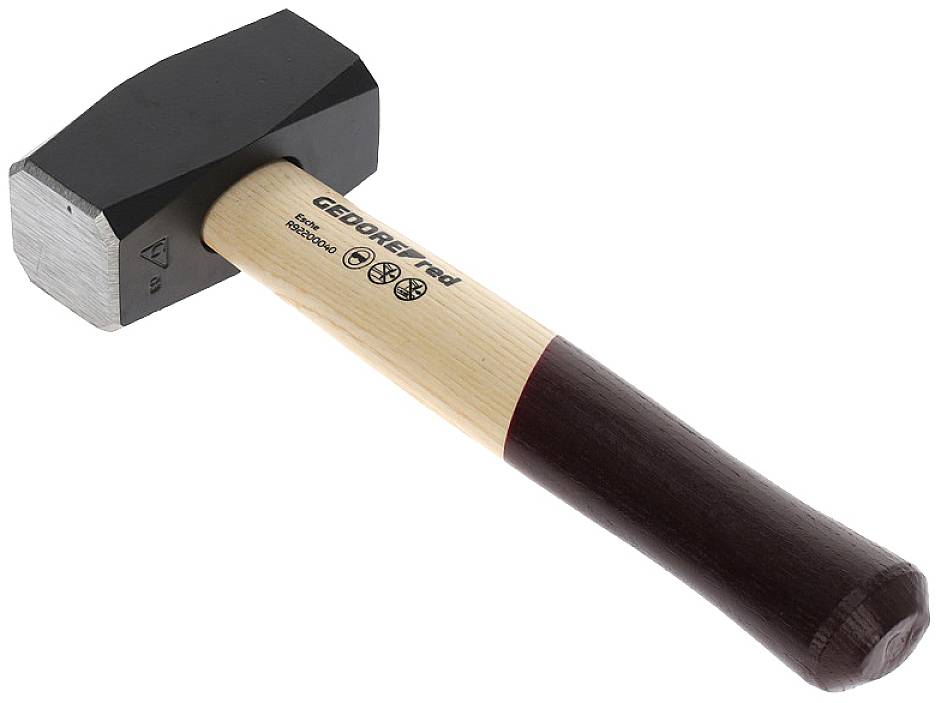 A hammer with a dark, square head and a wooden handle, partially painted in a dark colour, is lying at an angle. Markings are visible on the head.