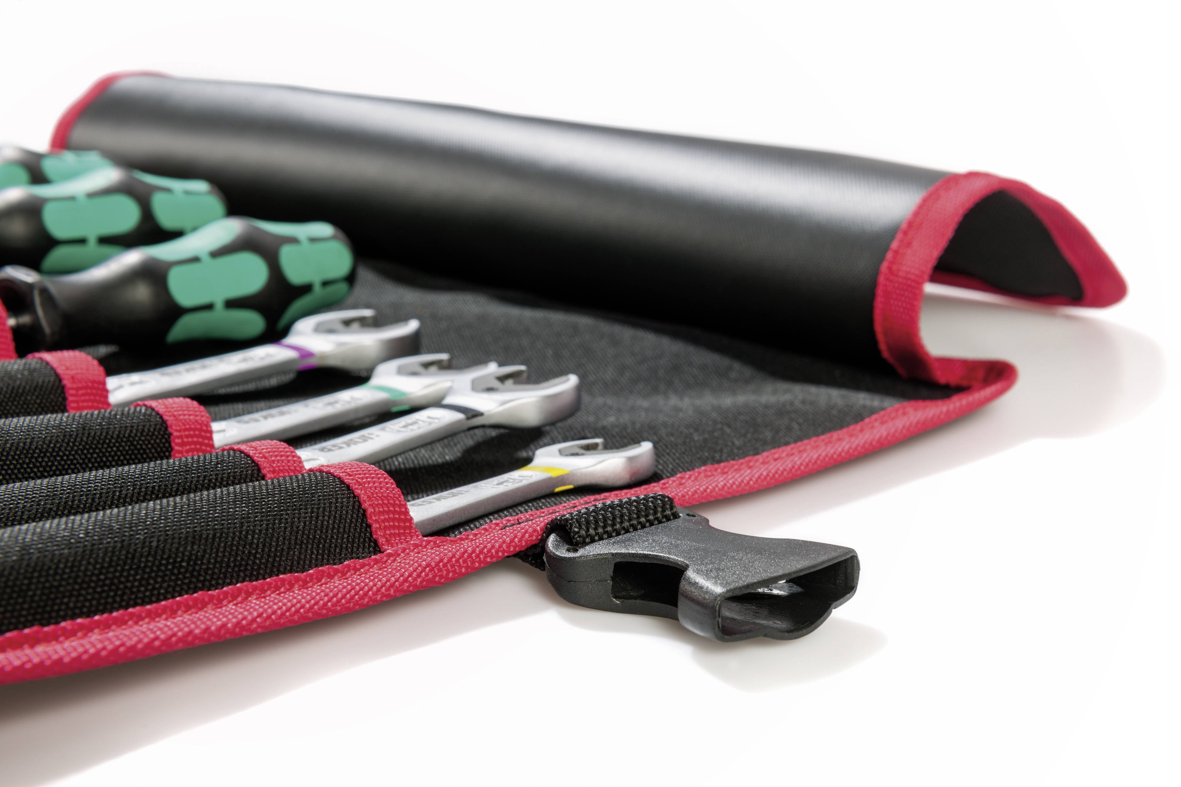 A set of spanners in a red-bordered tool bag with green handles, partially unrolled on a white surface.