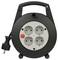 Black cable reel with four outlets and a red switch on the front, cable with plug coiled up on the side.