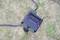An outdoor socket with two green sockets and a black cable lies on a lawn.