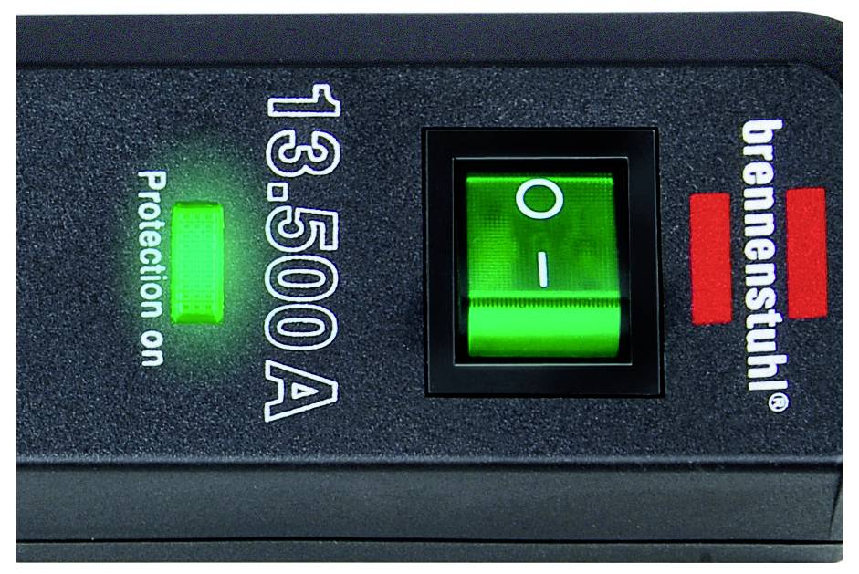 Close-up of a Brennenstuhl power strip switch showing a green illuminated on/off rocker and the text '13.500 A' and 'Protection on'.