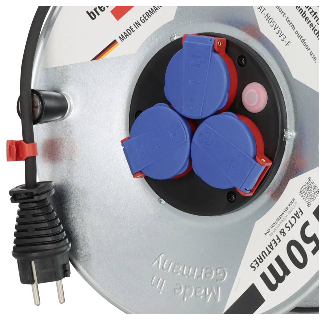Close-up of a portable cable reel with three blue covered outlets, a black power plug, and an integrated pink button on a silver spool.